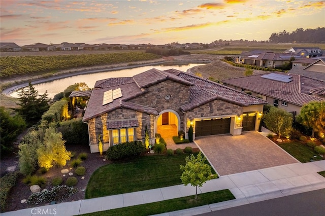 view of front of property with a garage, a yard, and a water view