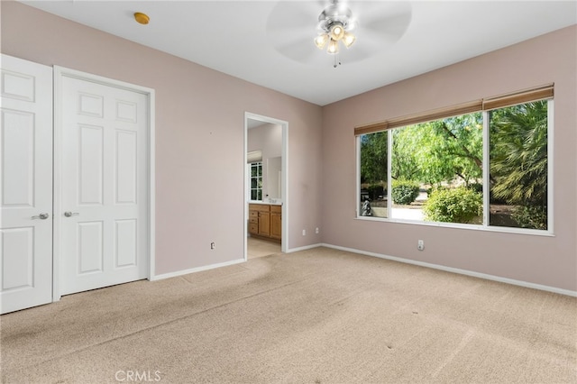 unfurnished bedroom featuring ceiling fan, connected bathroom, and light carpet