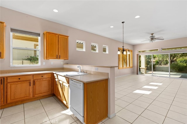 kitchen with light tile patterned floors, white dishwasher, a sink, light countertops, and a peninsula