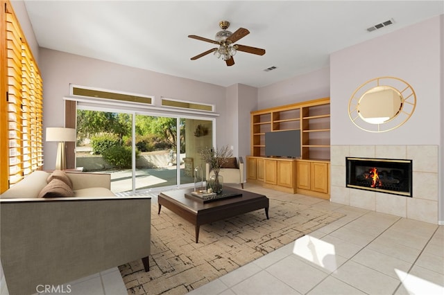 living room with a tiled fireplace, ceiling fan, and light tile patterned floors