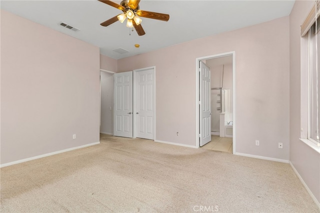 unfurnished bedroom with ceiling fan, light colored carpet, and ensuite bathroom