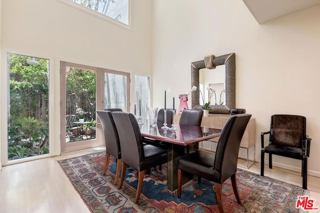 dining room with hardwood / wood-style flooring, plenty of natural light, and a towering ceiling