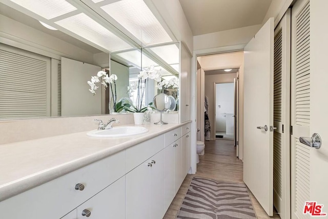 bathroom with hardwood / wood-style floors, vanity, and toilet