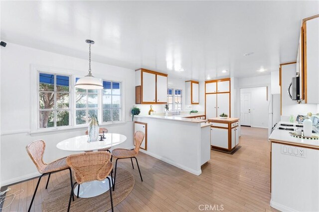 kitchen with pendant lighting, white cabinets, a center island, white refrigerator, and light hardwood / wood-style floors