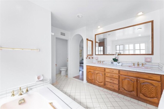 bathroom with toilet, vanity, tile patterned flooring, and a bathtub