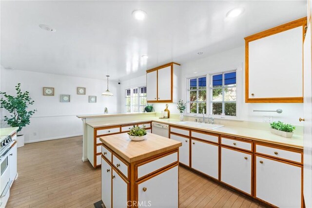 kitchen with kitchen peninsula, white cabinets, hanging light fixtures, and white appliances