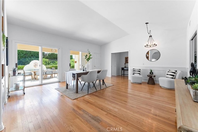 dining area featuring light wood-type flooring, vaulted ceiling, and an inviting chandelier