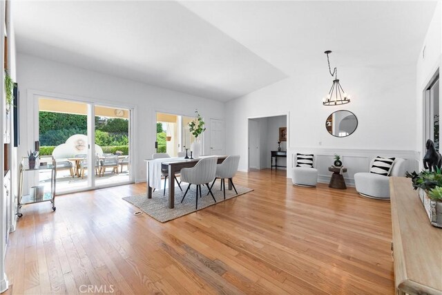 dining room featuring an inviting chandelier, vaulted ceiling, and light wood-style floors