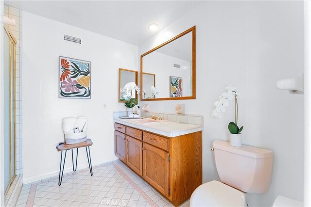 bathroom with tile patterned floors, visible vents, a shower with shower door, toilet, and vanity