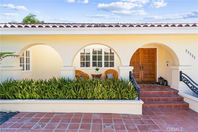 view of exterior entry featuring stucco siding and a tile roof