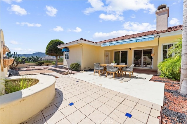 rear view of house with a patio area, a mountain view, stucco siding, and a tiled roof