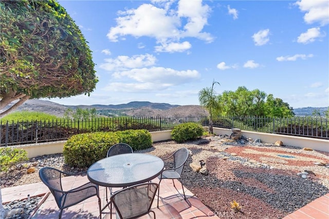 view of patio featuring outdoor dining space, fence, and a mountain view