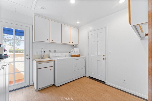 laundry area featuring cabinets, light hardwood / wood-style floors, separate washer and dryer, and sink