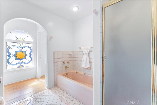 full bath featuring tile patterned flooring, a stall shower, a bath, and baseboards