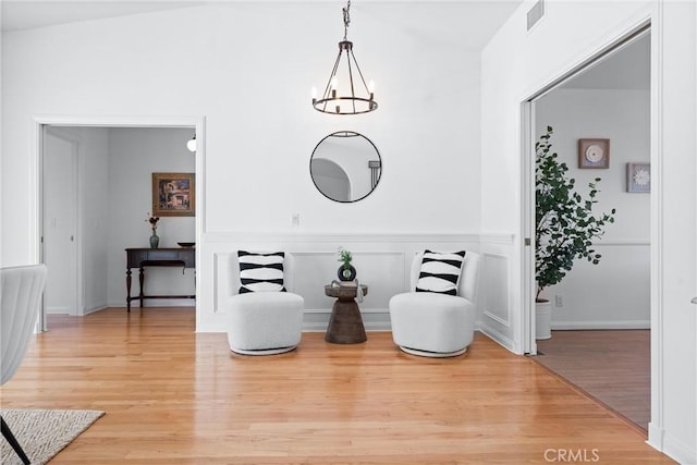 sitting room with an inviting chandelier, light wood-style flooring, visible vents, and wainscoting