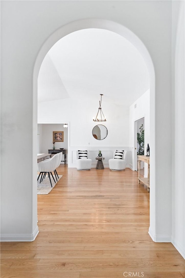 corridor featuring light wood-style floors and arched walkways