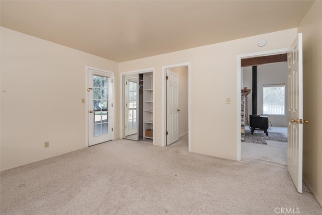 spare room with light carpet and a wood stove