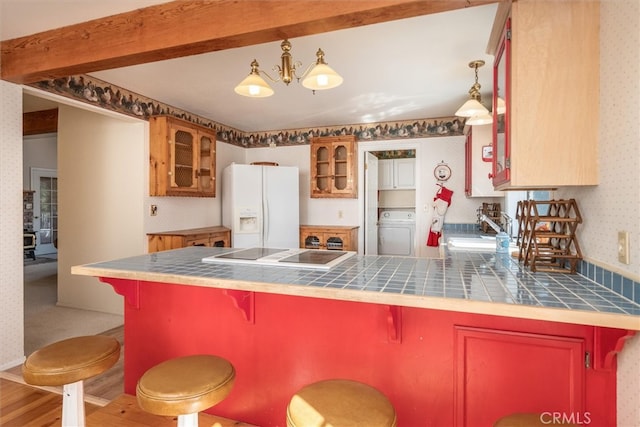 kitchen featuring sink, decorative light fixtures, washer / clothes dryer, tile countertops, and white fridge with ice dispenser