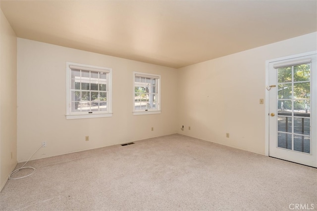 spare room with light carpet and plenty of natural light