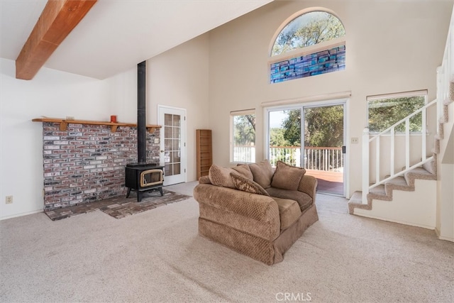 carpeted living room with beamed ceiling, a high ceiling, and a wood stove