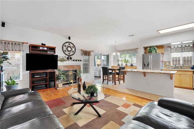 living room featuring a chandelier, light hardwood / wood-style floors, a fireplace, and sink