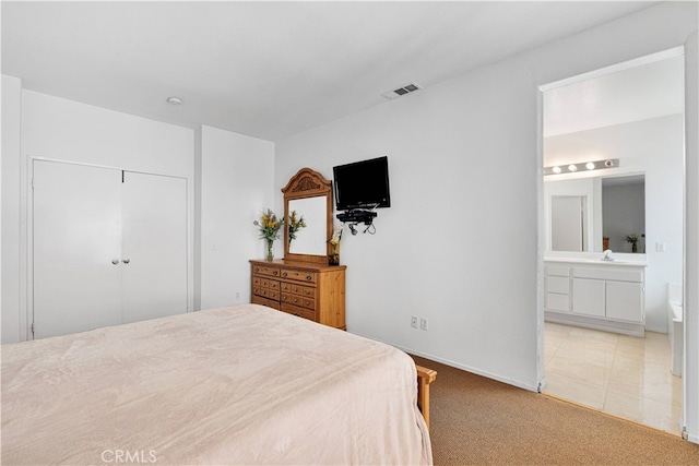 bedroom featuring light carpet, a closet, and connected bathroom