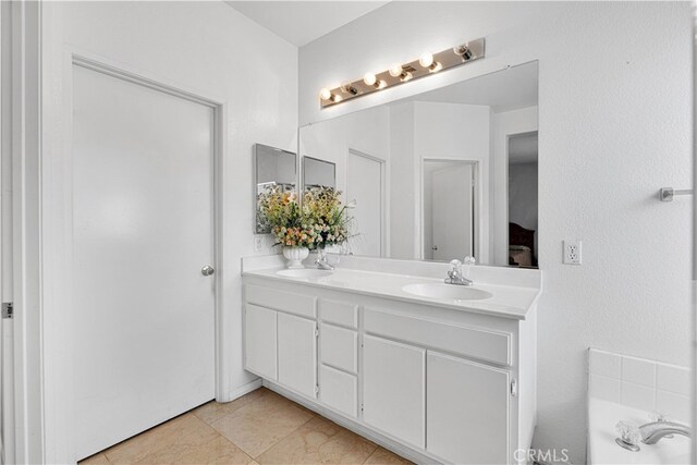 bathroom with tile patterned floors, a bath, and vanity