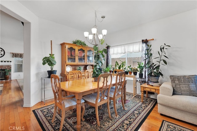 dining room with a notable chandelier, a fireplace, and light hardwood / wood-style floors