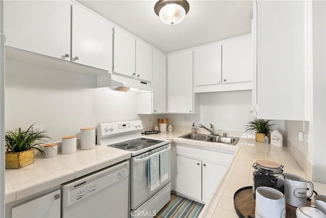 kitchen with tile countertops, dishwasher, sink, range with electric cooktop, and white cabinetry