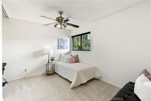 bedroom with ceiling fan, light carpet, and a textured ceiling