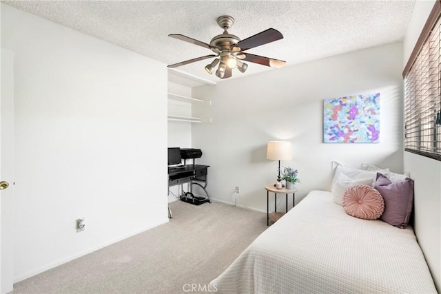 carpeted bedroom with ceiling fan and a textured ceiling