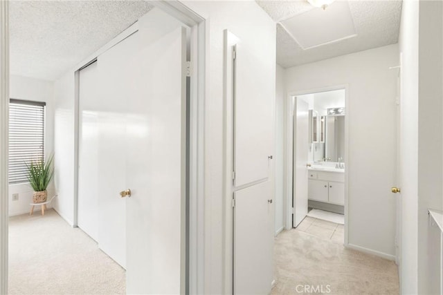 hallway featuring light carpet and a textured ceiling