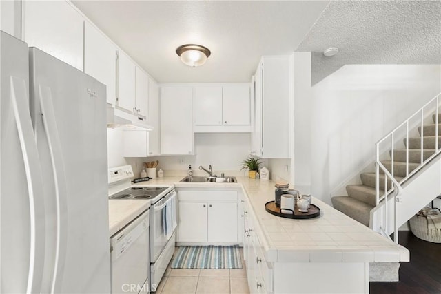 kitchen featuring light wood-type flooring, a textured ceiling, white appliances, sink, and white cabinetry