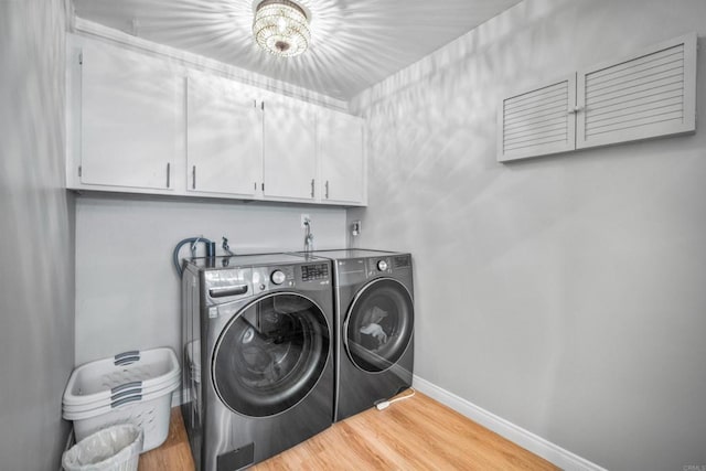 laundry area with washer and clothes dryer, light hardwood / wood-style flooring, cabinets, and a notable chandelier