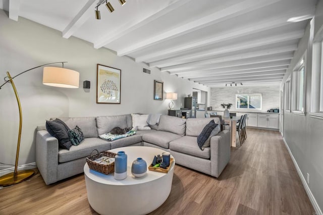 living room featuring beamed ceiling and light hardwood / wood-style floors