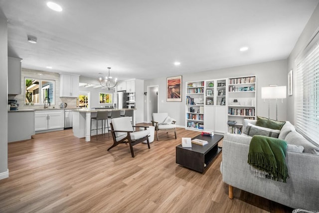 living room featuring light hardwood / wood-style flooring, a chandelier, and sink