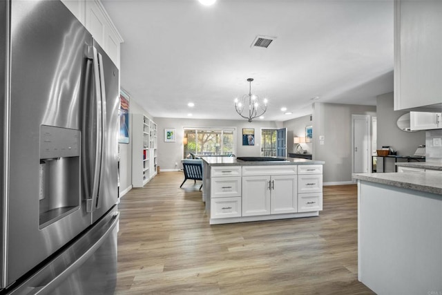 kitchen with stainless steel refrigerator with ice dispenser, decorative light fixtures, an inviting chandelier, white cabinets, and light hardwood / wood-style floors