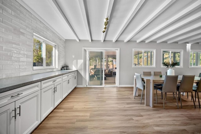 dining room with beamed ceiling and light hardwood / wood-style floors