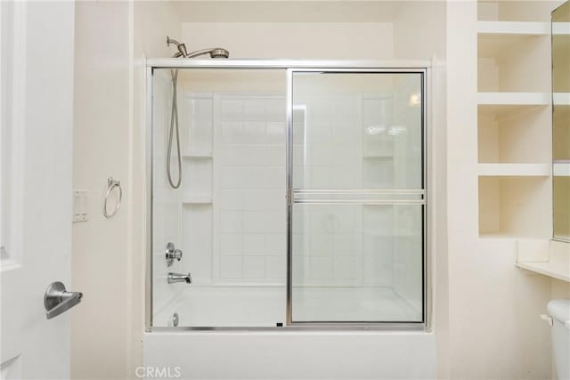 bathroom with combined bath / shower with glass door and toilet