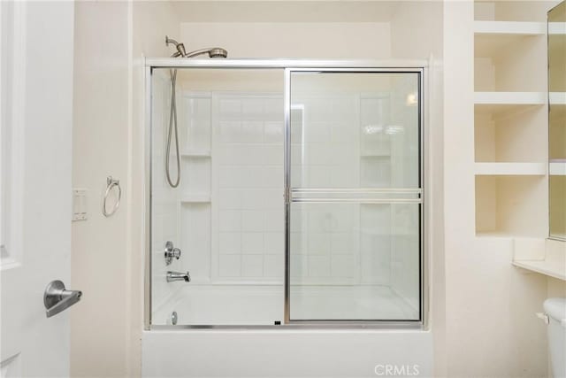 bathroom with shower / bath combination with glass door and toilet