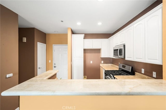 kitchen with white cabinets, kitchen peninsula, and appliances with stainless steel finishes