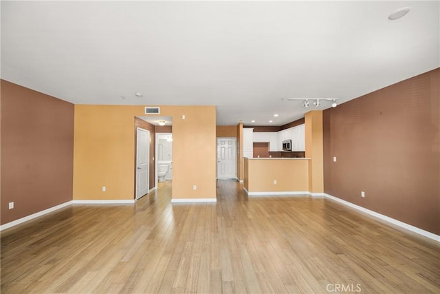 unfurnished living room with rail lighting and light hardwood / wood-style flooring