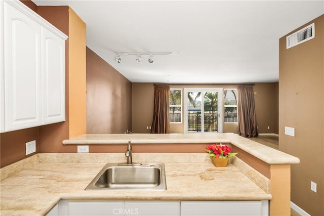 kitchen with sink, white cabinetry, and rail lighting