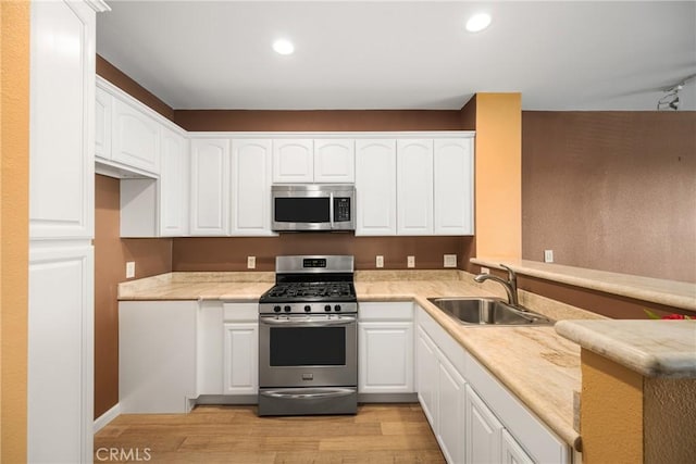 kitchen with white cabinets, sink, stainless steel appliances, and light hardwood / wood-style flooring