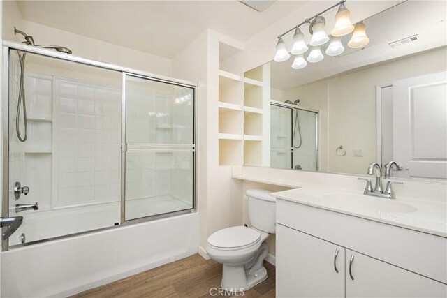 full bathroom with combined bath / shower with glass door, vanity, toilet, and hardwood / wood-style floors