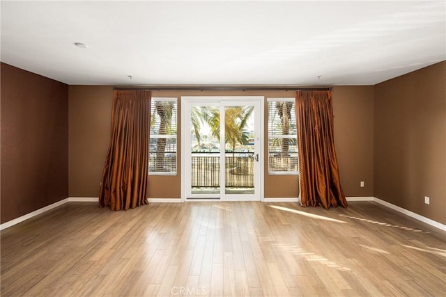 spare room with plenty of natural light, baseboards, and wood finished floors