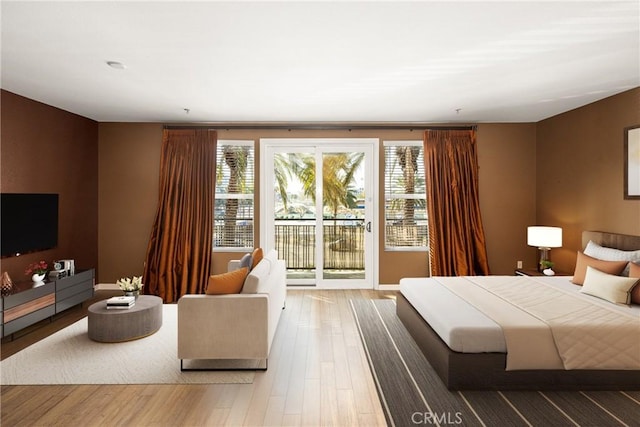 bedroom with access to outside, multiple windows, and wood finished floors