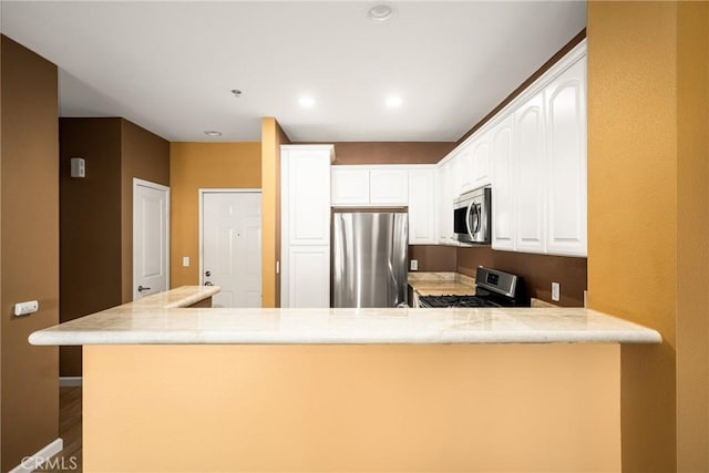 kitchen with appliances with stainless steel finishes, white cabinets, and a peninsula