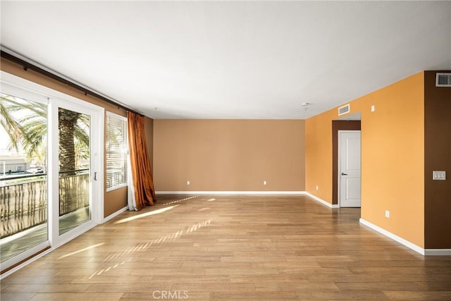 unfurnished room featuring baseboards, visible vents, and light wood-style floors