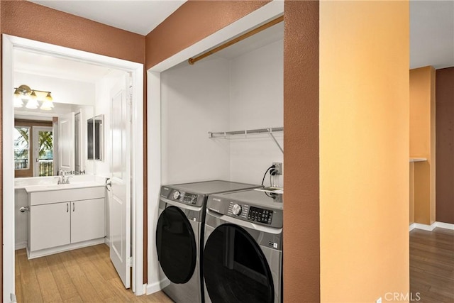 washroom with baseboards, separate washer and dryer, a sink, and light wood-style floors